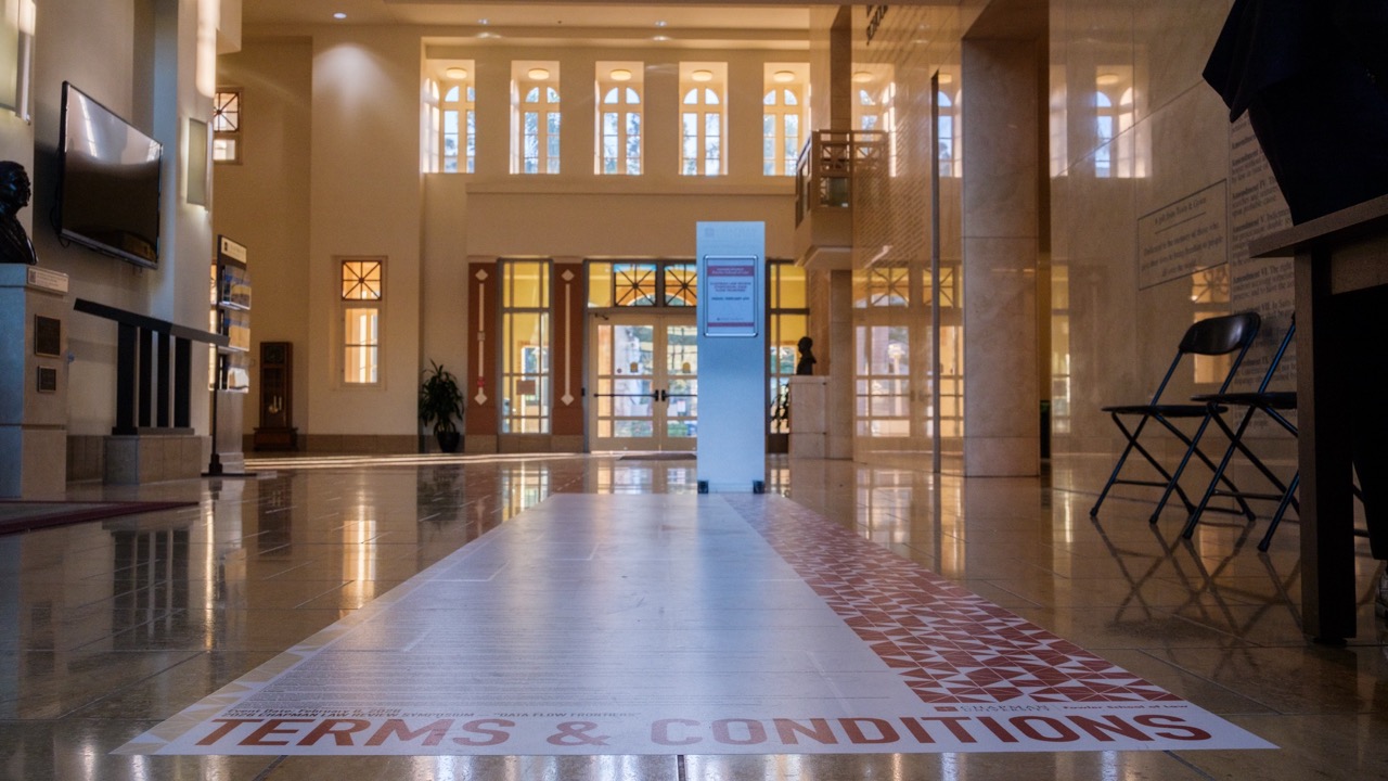 Interior of the law school with a vinyl sticker displaying the terms and conditions of the event in the foreground.