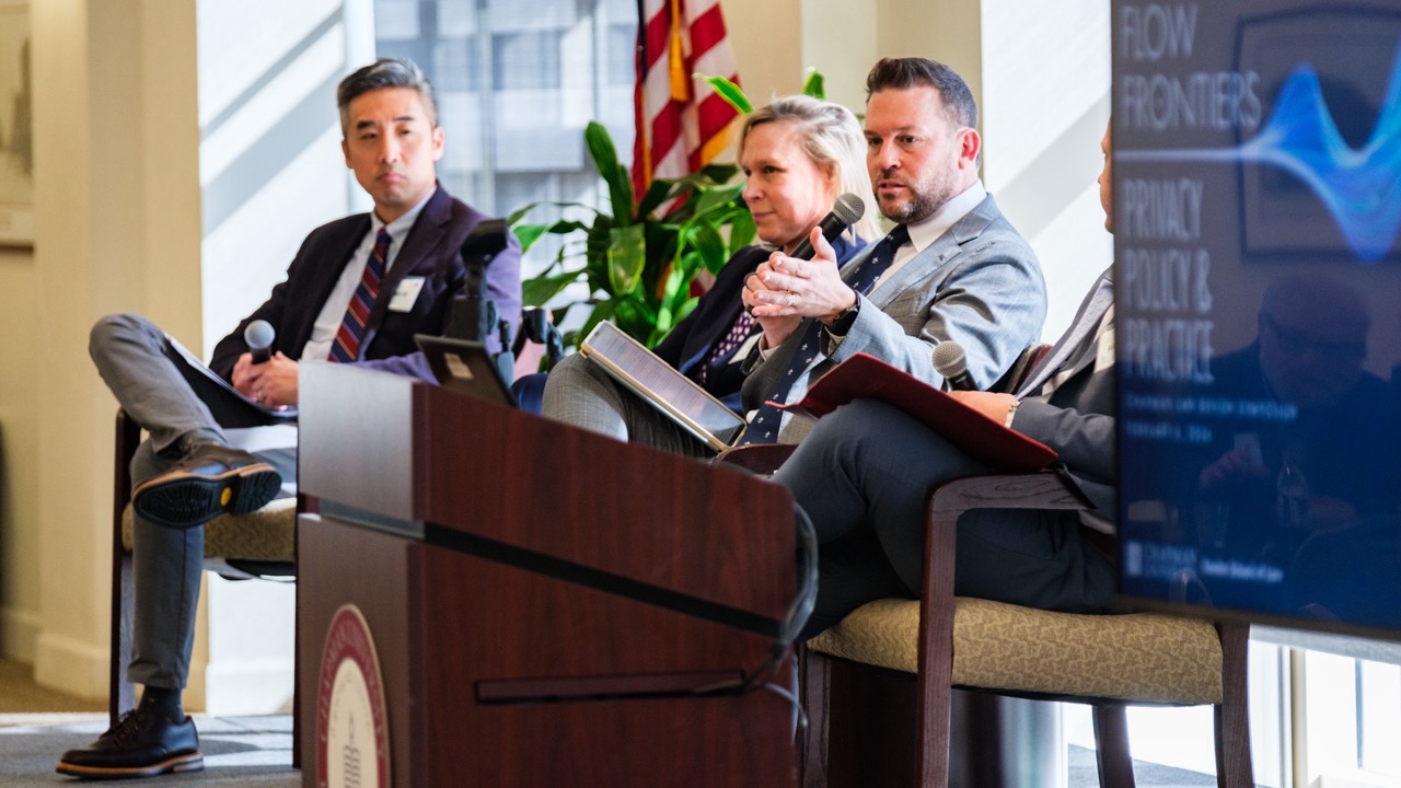 A panelist raises his hand to make a point to the audience.
