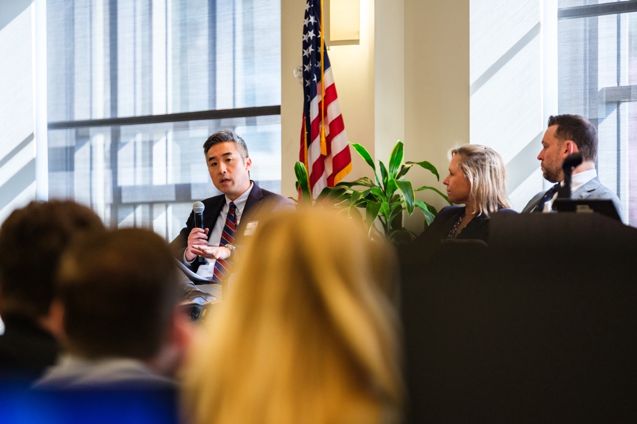 A panelist pictured on stage making a point to the audience.