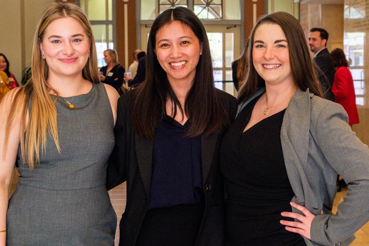 Three students pose at the en banc following the symposium