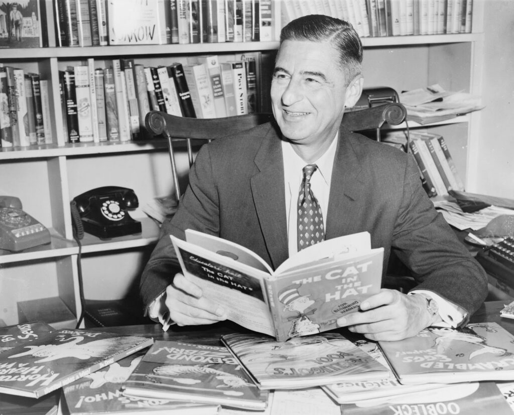 Author Dr. Seuss holding The Cat in the Hat and smiling.