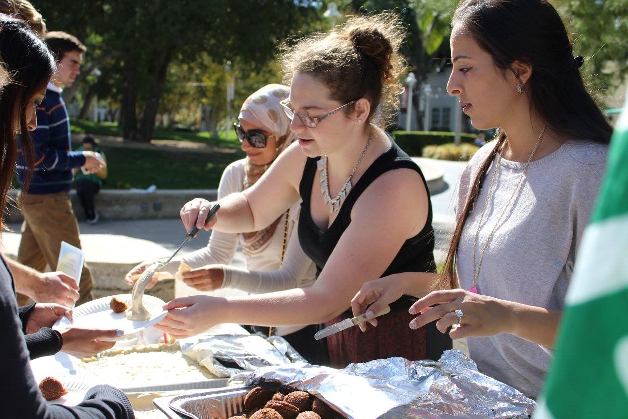 Group of people serving food from dessert table.