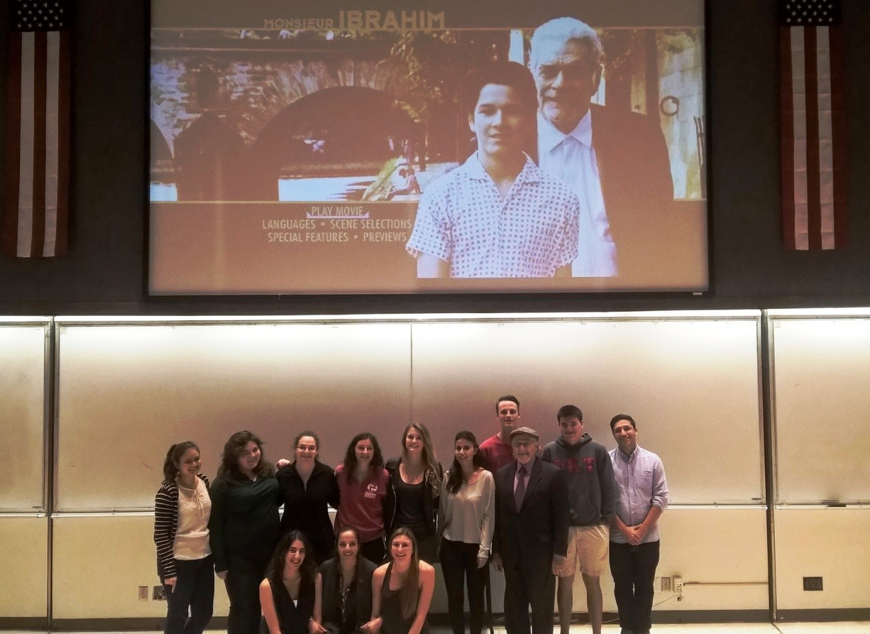 Group of people posing in front of movie on projector screen.