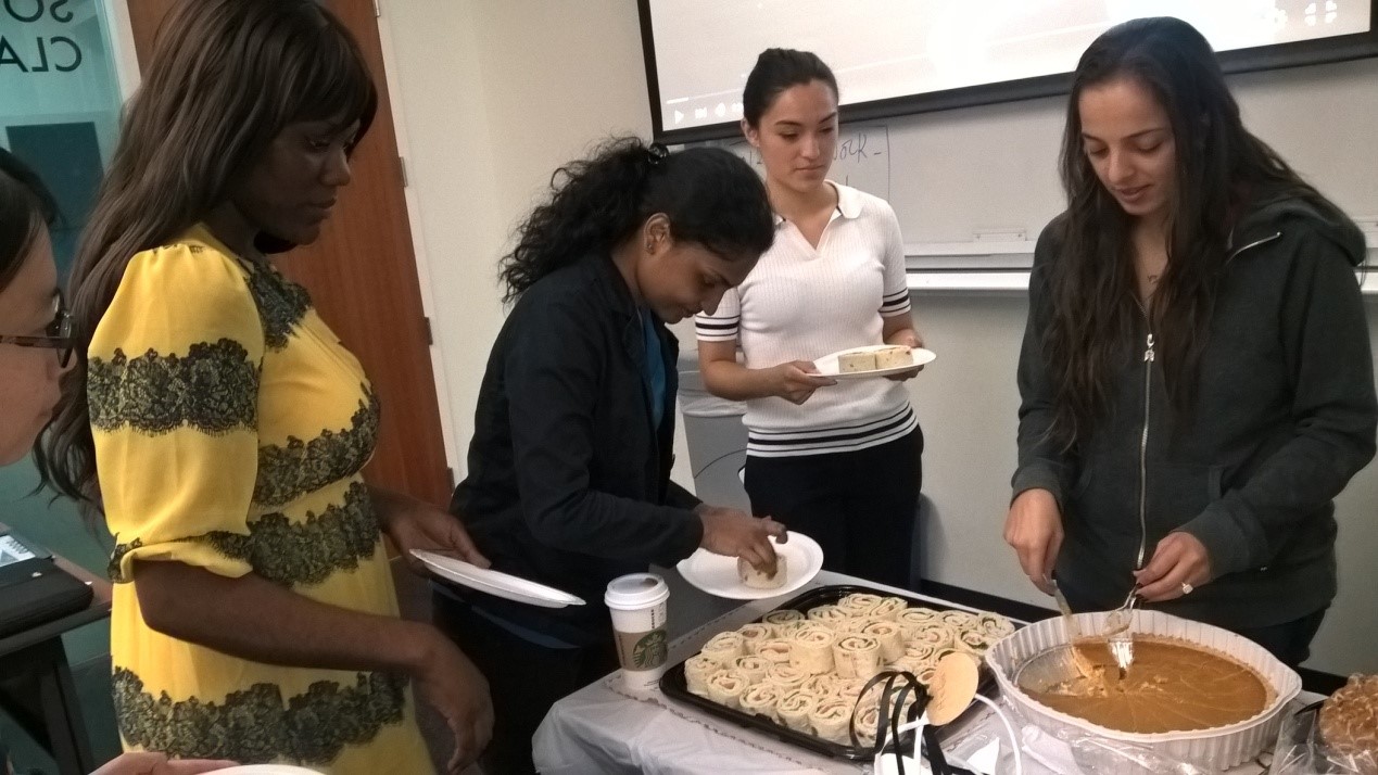 Group of people serving themselves food from dessert table.