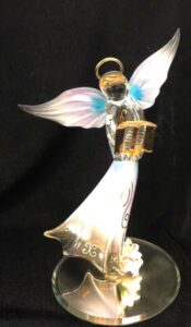 A small glass figurine of an angel reading a book.