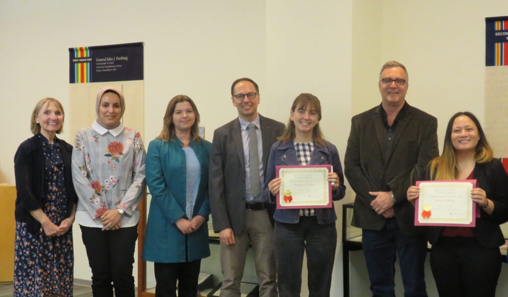 Two winners stand amidst library staff and judges of the contest.