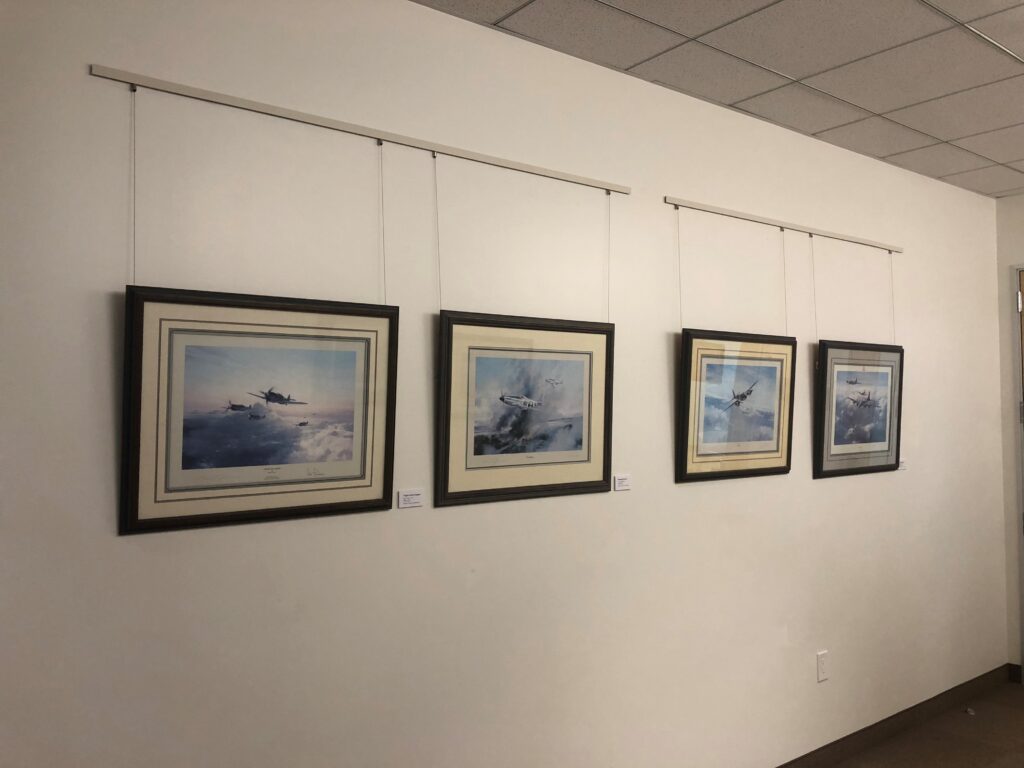 Four lithographs of aircraft hanging on a white wall.
