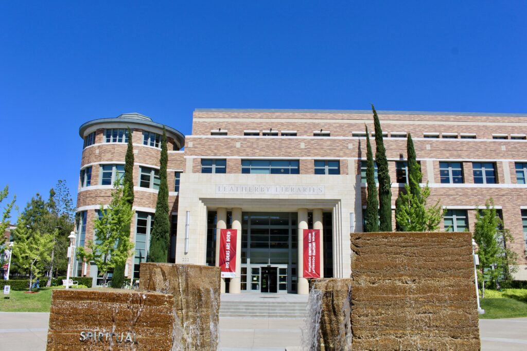 Exterior shot of the Leatherby Libraries, photographed from behind the Attallah Piazza fountain, with the top of the fountain visible in the foreground