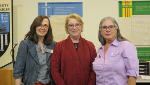 Three women stand posing for the camera.