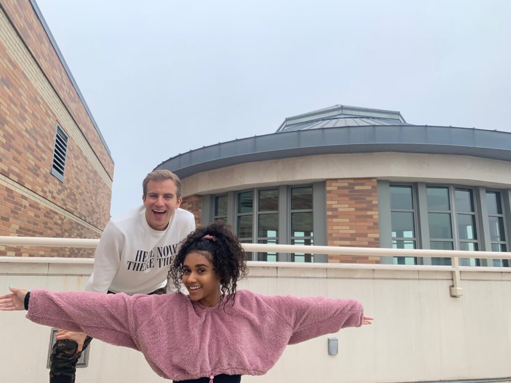 Ruby Blakesleay, in a pink sweater, poses in front of Jimmy Elinski, on a patio of the Leatherby Libraries