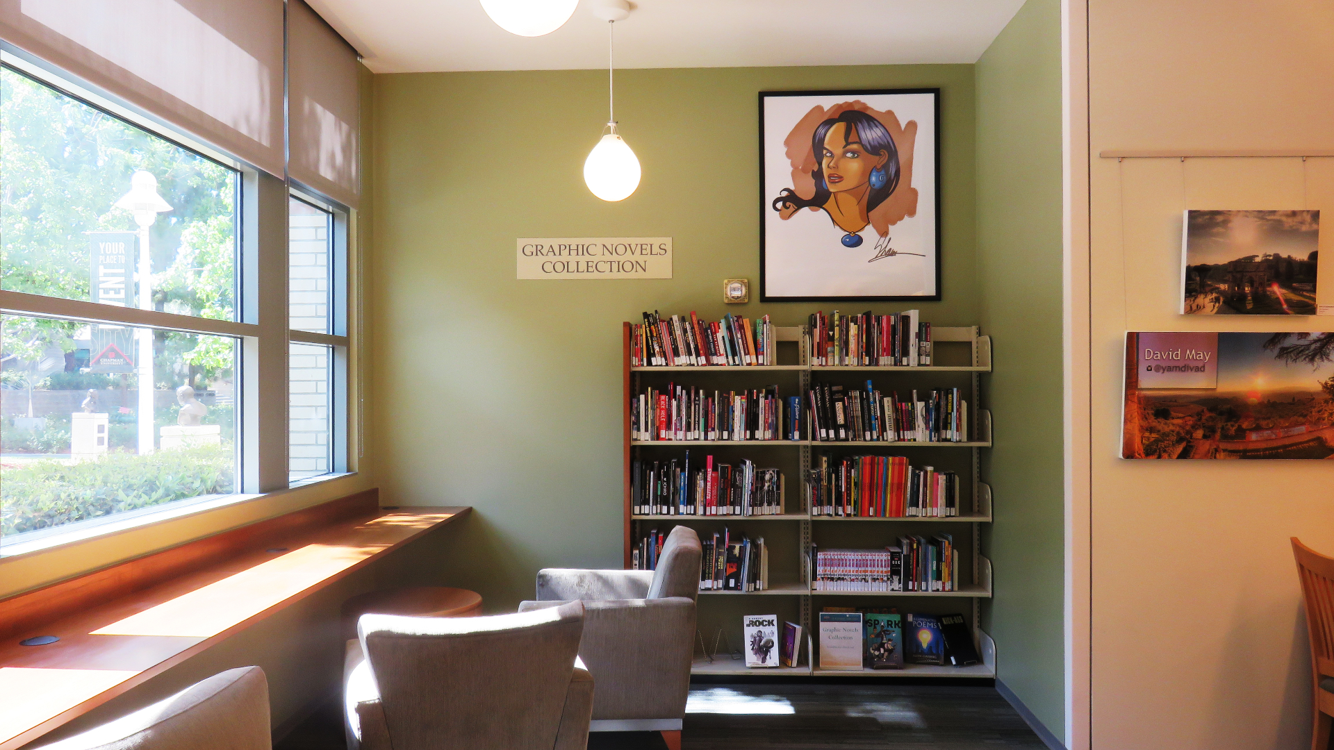 The Graphic Novels Collection corner of the Leatherby Libraries - a bookshelf filled with graphic novels, and two armchairs