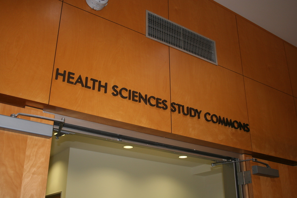 Photograph of the outside of the Health Sciences Study Commons, showing those words on a wooden wall over an open door