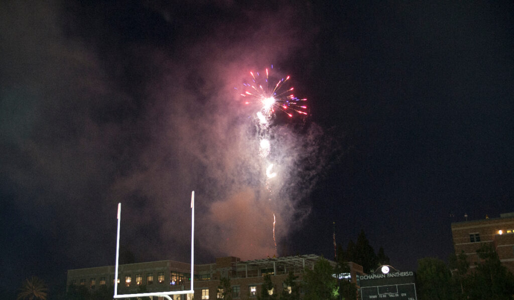 Red fireworks exploding in a dark night sky over the Wilson Football Field.