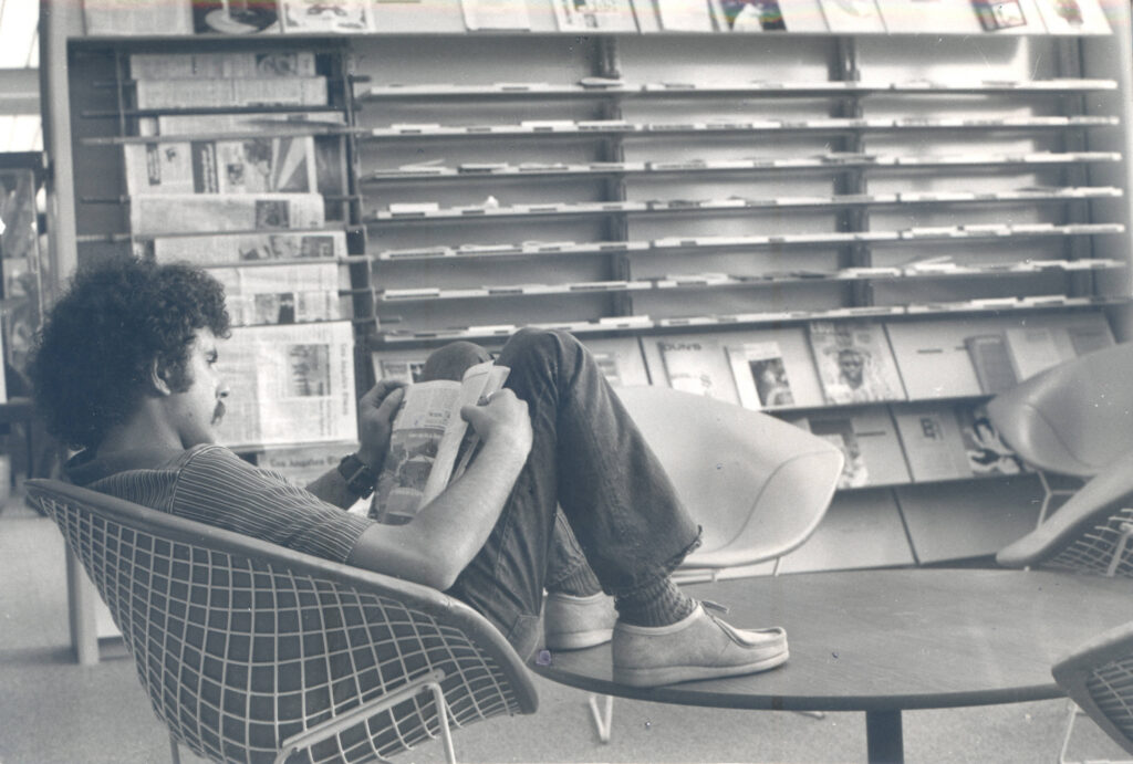 Black and white picture of a male student reading a book in the Thurmond Clarke Memorial Library