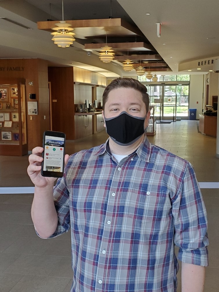 A man in a mask holding up a cell phone