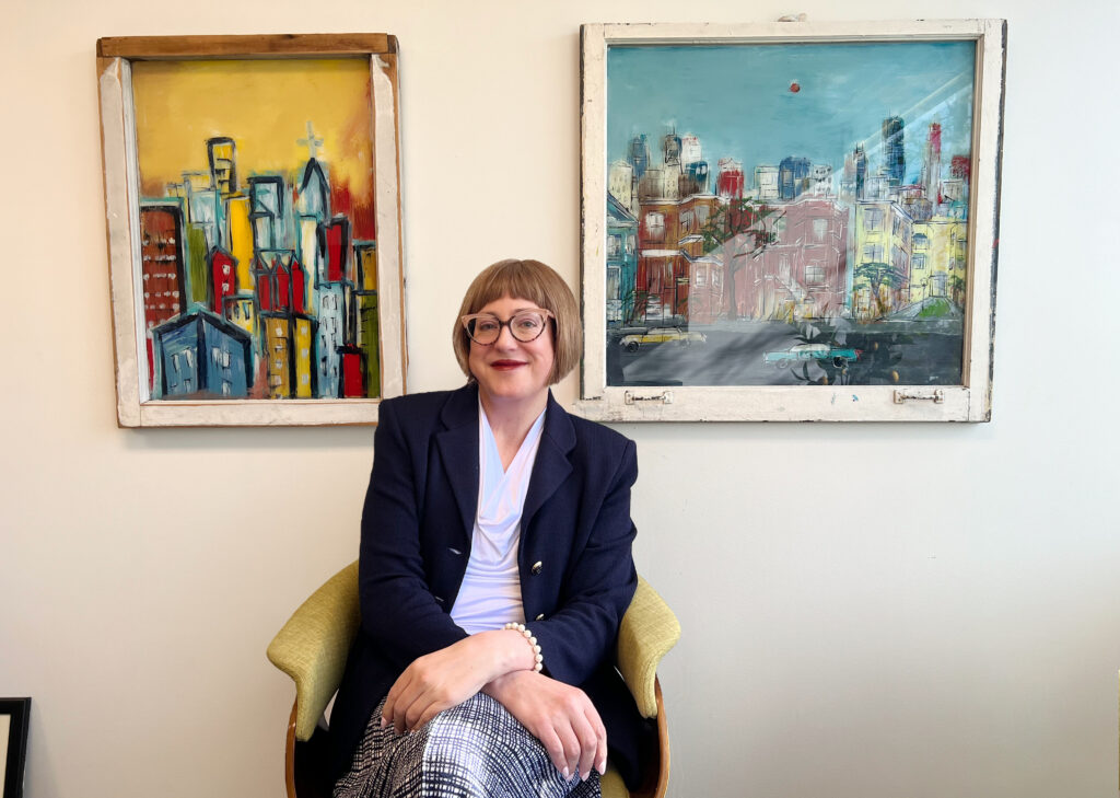 Dr. Dintzner sitting with two paintings in her office