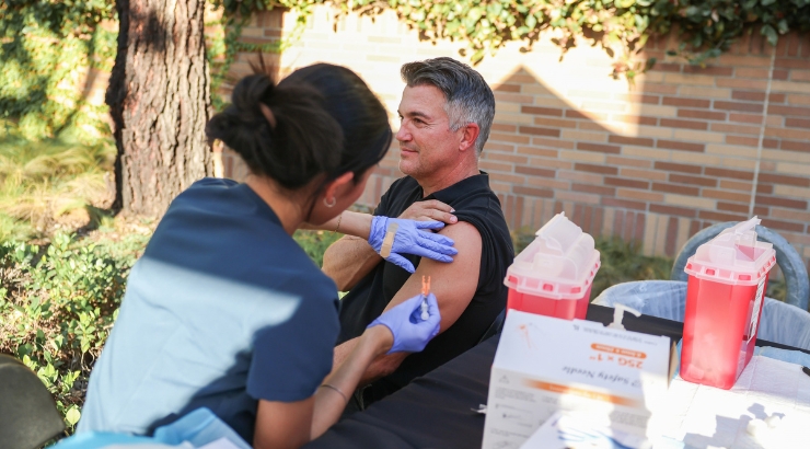 CUSP Student Pharmacist administering a flu vaccine to a Homecoming attendee