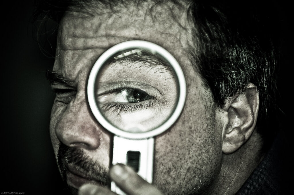 Someone with their eye to a magnifying glass