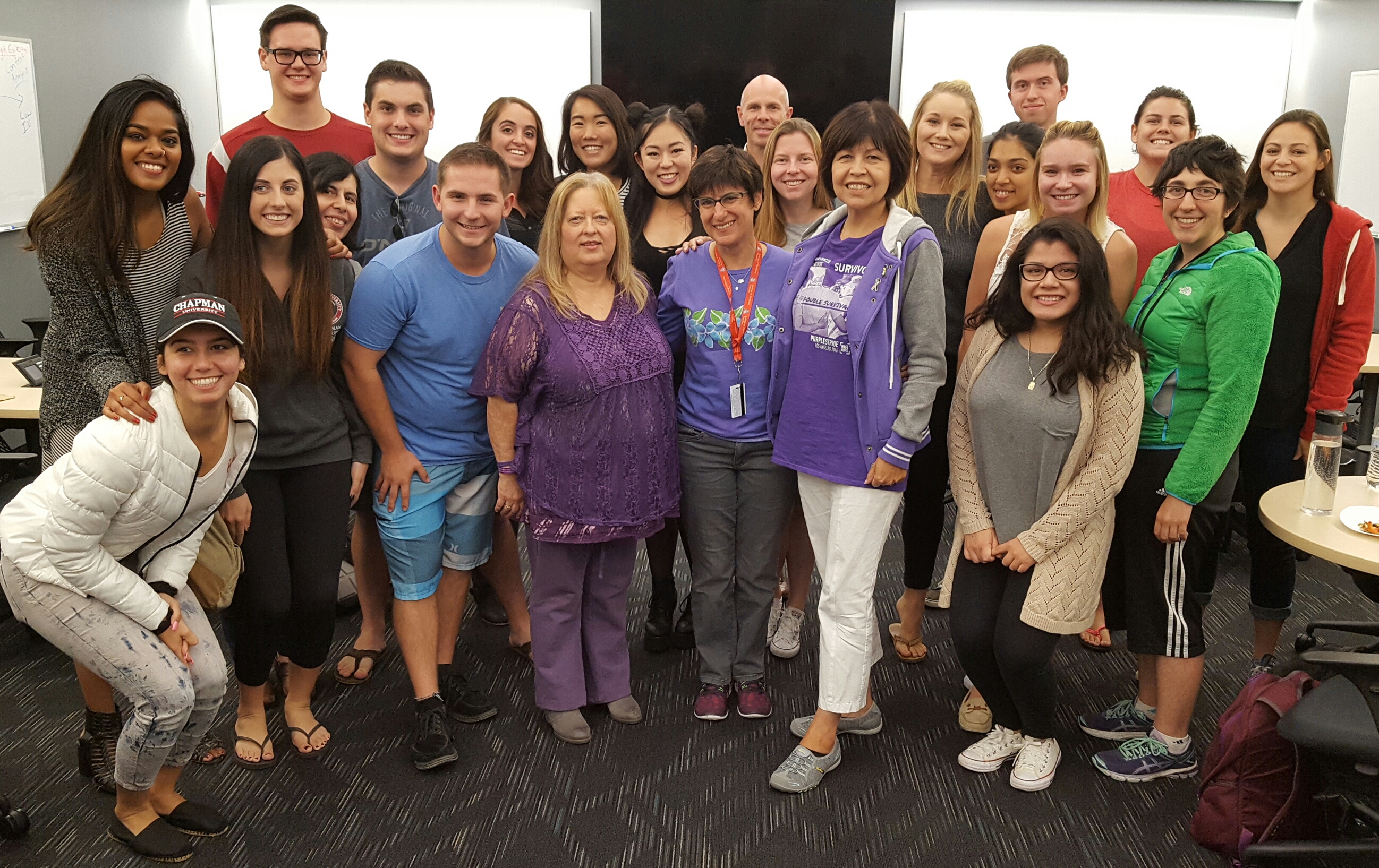 Pancreatic cancer survivors Roberta Luna (front left in purple) and Lupe Romero (front-right in purple) stand with Prof. Melissa Rowland-Goldsmith (front-center in purple) and the students in the Cancer Biology class she co-teaches with Prof. Marco Bisoffi (back center).