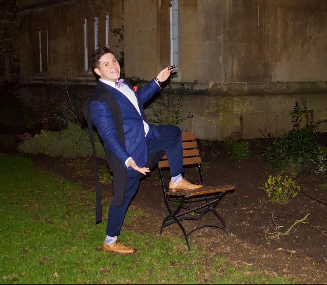 Vidal posing with one foot on ground, and one foot on chair