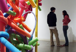 Two people in art gallery with sculpture.
