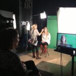 Woman being filmed in front of green screen.
