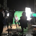 Man being filmed in front of green screen.