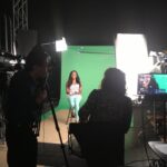 Woman being filmed in front of green screen.