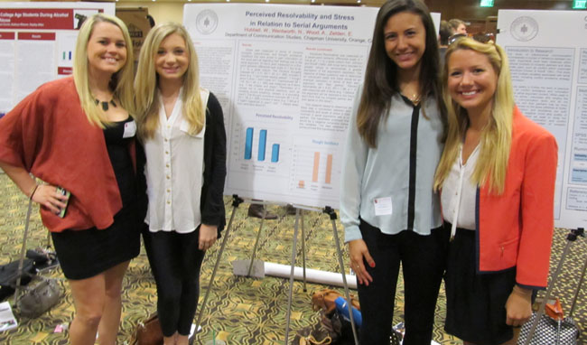 Group of people smiling next to presentation boards.