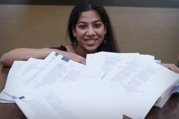 Woman posing with many marked up pages of writing.