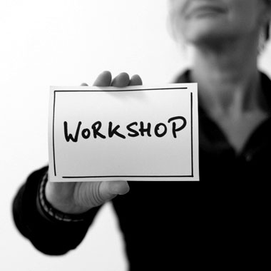 Woman holding flashcard with "workshop" written on it.