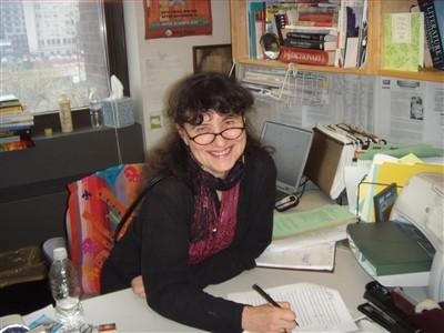 Woman at desk writing and smiling.