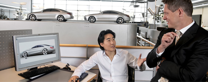 Two men talking at computer with car design.