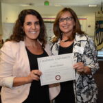 Two women pose with award.