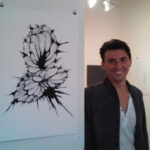 Man smiling next to art.