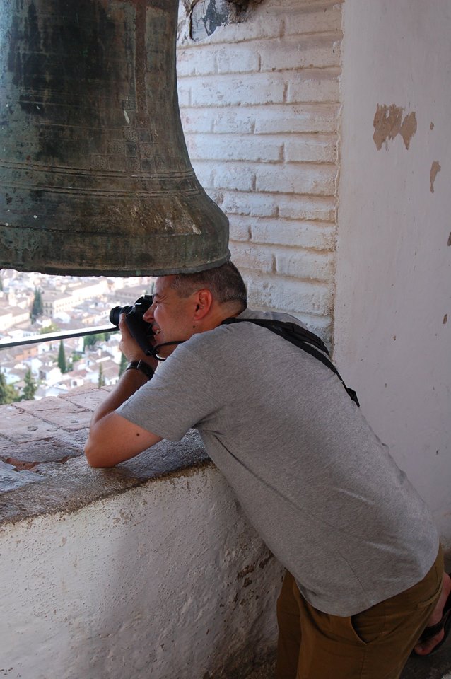Man in bell tower taking photo.