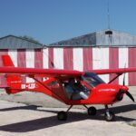 Small plane with man in it as another man takes photo.