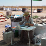 Woman filling out paperwork at outdoor desk.