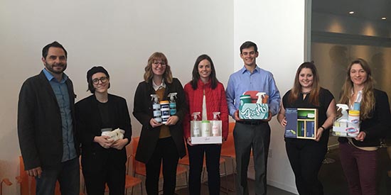 Group of people smiling and holding cleaning items.