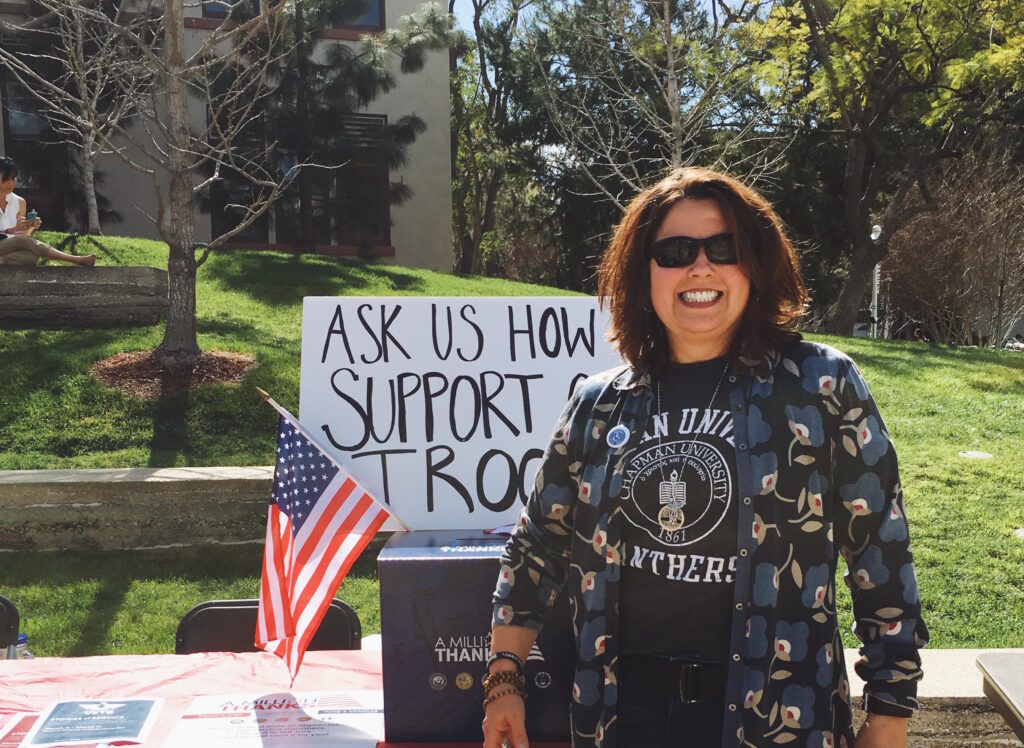 Woman smiling next to fundraising table for military.