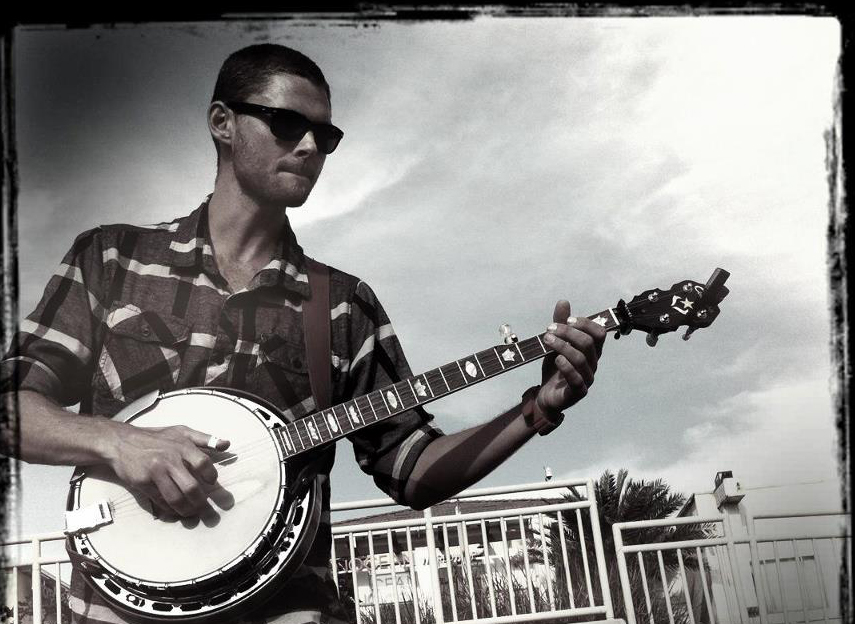Man playing banjo outside.