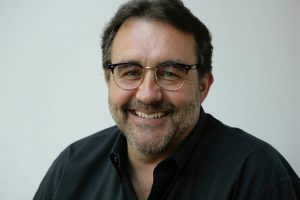 man's face smiling with short beard and glasses