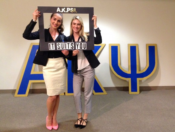 Students posing in front of AKPSI logo