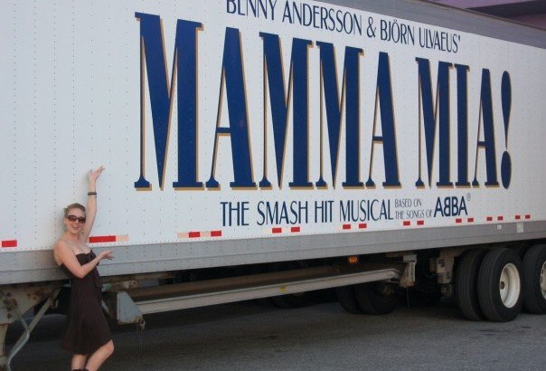 Woman standing next to truck with Mamma Mia! logo.