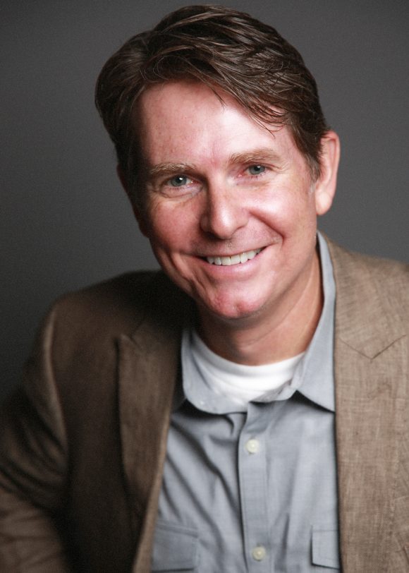 Smiling middle-age man with short brown hair in sport coat and unbuttoned collard shirt