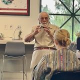 Elderly man with white beard lecturing.