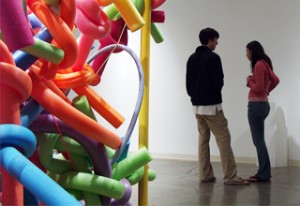 Two people in art gallery with sculpture.