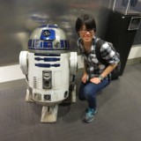 Digital Arts student poses in front of replica of Star Wars character R2D2