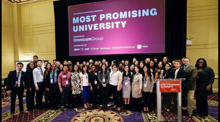 large group standing in front of a screen that says most promising university
