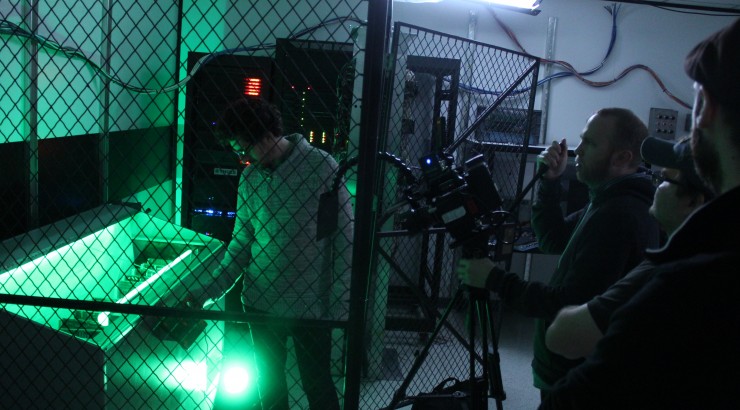 green lit storage room with man inside and cameras pointed at him